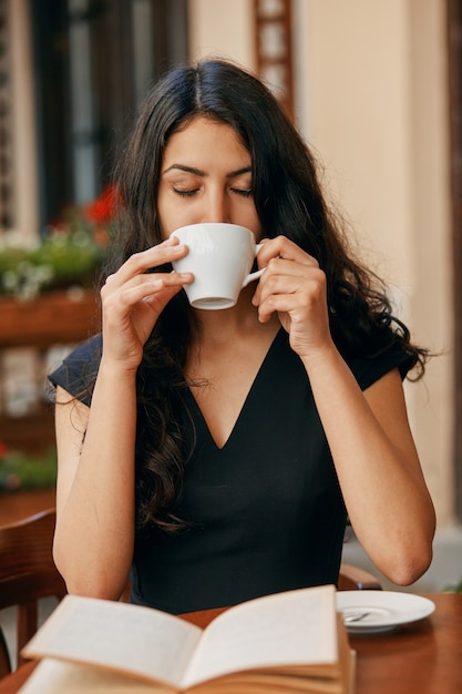 Happy young Arabic woman drinking coffee at a cafe