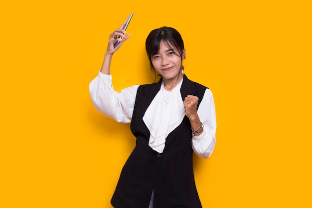 happy young asian beautiful woman using mobile phone isolated on yellow background