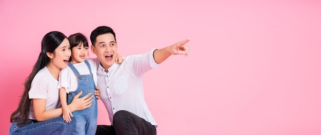 Happy young asian family image isolated on pink background