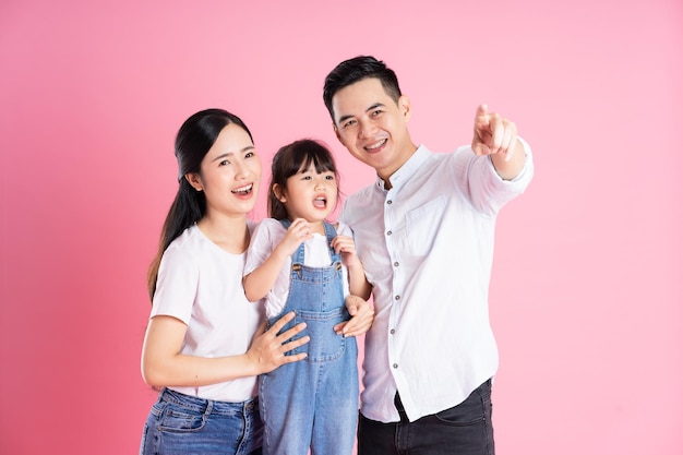 Happy young asian family image isolated on pink background