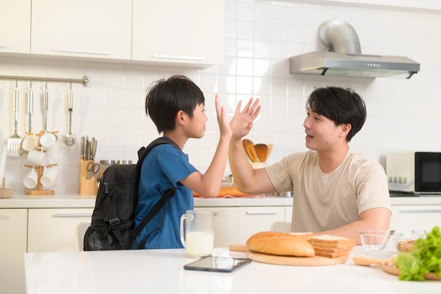 Happy Young Asian father encouraging to his son to go to school