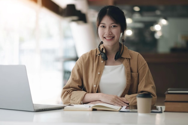 Happy young Asian student woman wearing headphones looking at webcam looking at camera during virtual meeting or video call talkxA