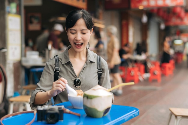 Happy young Asian woman backpack traveler enjoying street food at China town street food market in Bangkok Thailand Traveler checking out side streets