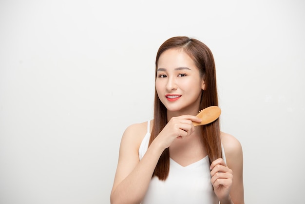 Happy young Asian woman combing her hair