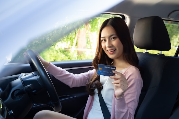 Happy young Asian woman holding payment card or credit card and used to pay for gasoline, diesel, and other fuels at gas stations, Driver with fleet cards for refueling car