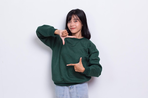 Happy young asian woman pointing with fingers to different directions isolated on white background