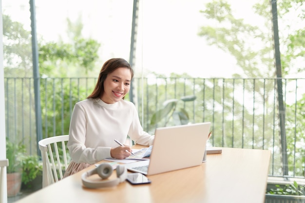 Happy young Asian woman relax sitting on desk do job in internet