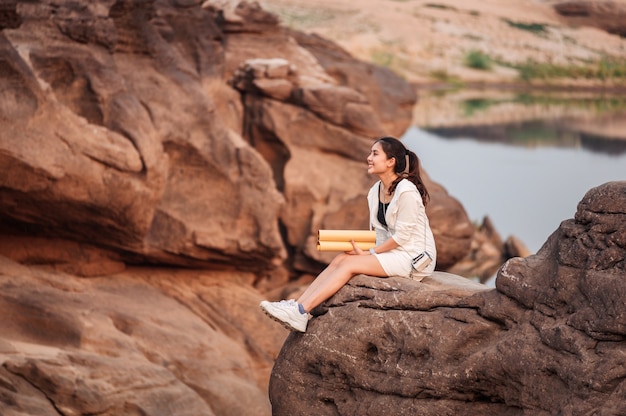 Happy young asian woman traveler with paper map on rock cliff in grand canyon of Thailand