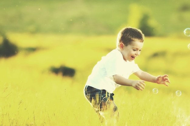 happy young beautiful child have fun on eadow with soap bubbles toy