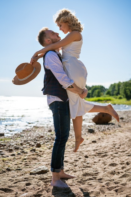 Happy young beautiful couple in arms on the beach on a Sunny day. The concept of the relationship