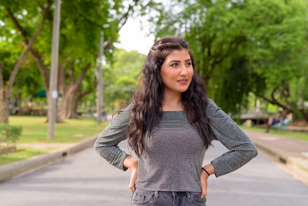 Happy young beautiful Indian woman thinking in the streets at the park