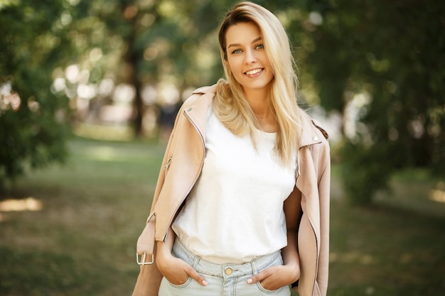 Happy young beautiful model woman in fashionable pink jacket outdoor nature