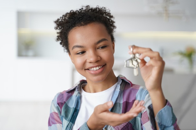 Happy young biracial girl tenant show house key to new home Real estate rental service relocation