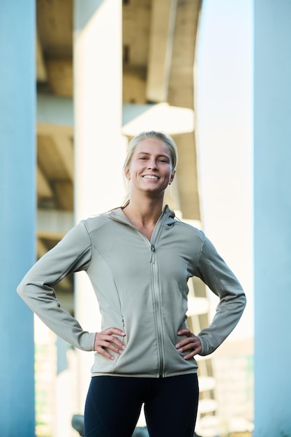 Happy young blond female athlete with toothy smile standing in urban environment