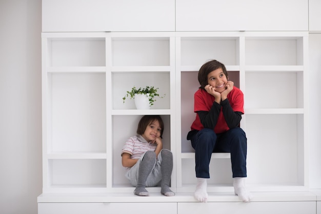 happy young boys are having fun while posing on a shelf in a new modern home