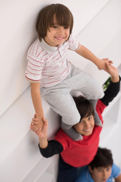 happy young boys having fun and posing line up piggyback in new modern home top view