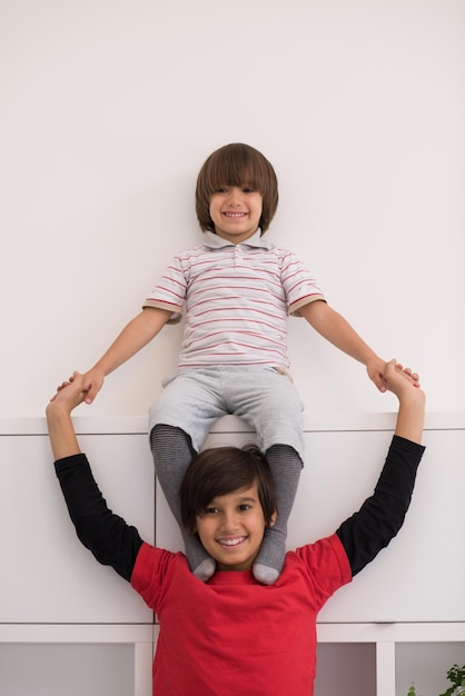 happy young boys having fun and posing line up piggyback in new modern home