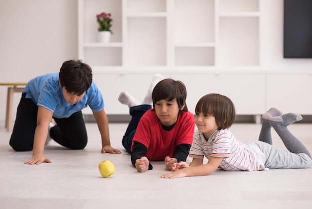 happy young boys having fun with an apple on the floor in a new modern home