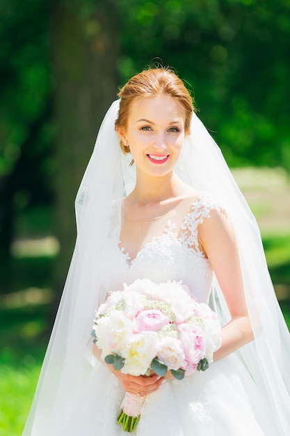 Happy young bride in a delicate white wedding dress and veil in