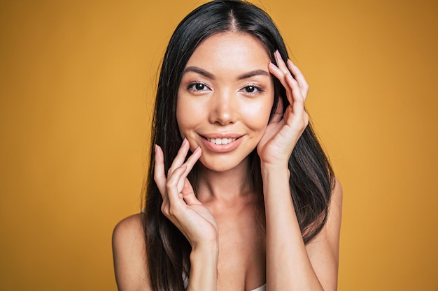 Happy young brunette asian woman portrait on yellow background