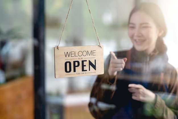 Happy young business owner standing with open sign board.