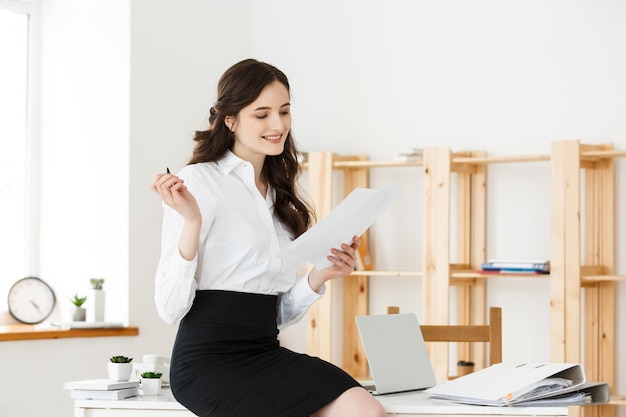 Happy young business woman or secretary holding document in modern office