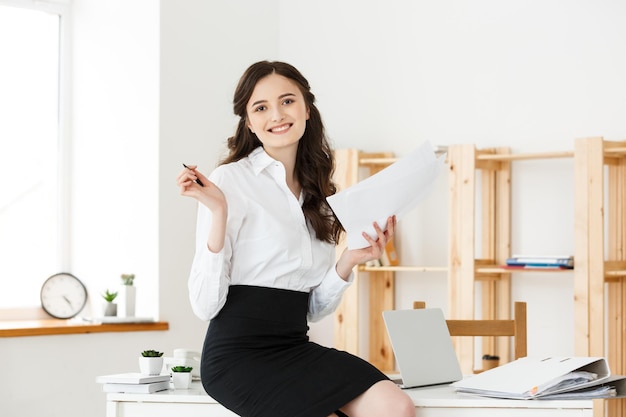 Happy young business woman or secretary holding document in modern office