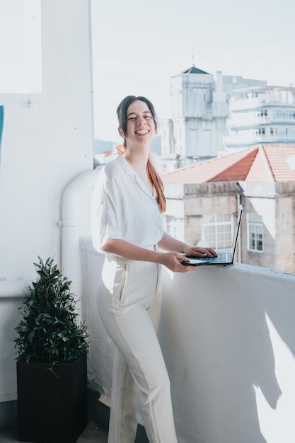 Happy young businesswoman working on laptop outdoorsworking on a laptop on the terrace Satisfied female remote worker with laptop portrait young woman professional manager working on pc computer