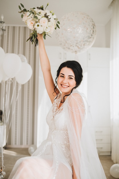 Happy young Caucasian bride sitting and holding her wedding bouquet