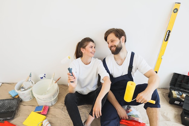 Happy young caucasian couple holding paint rollers during renovation