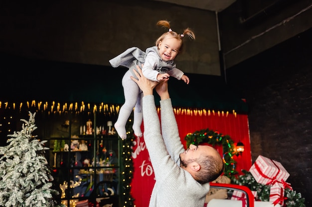 Happy young Caucasian father Playing with small daughter on Christmas background. Family. Fun. New Year winter holidays.