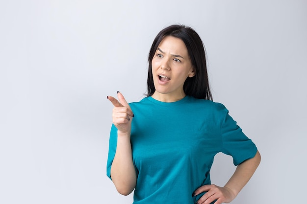 Happy young caucasian female in a blue t-shirt pointing fingers away