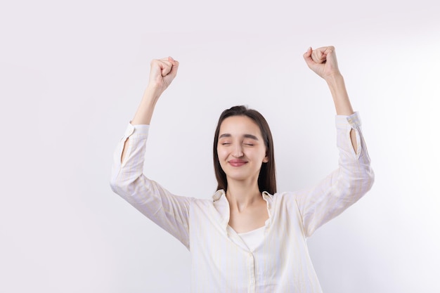 Happy young caucasian female wearing a white shirt clenched fist up for joy Success and happiness of the work Successful person victory