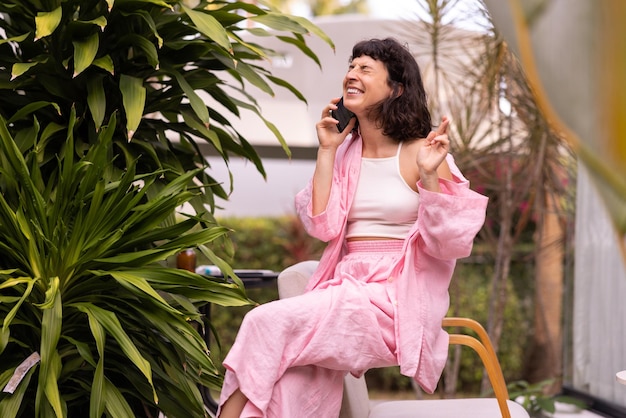 Happy young caucasian girl squints eyes closed calls on phone crosses fingers sitting on street Happy weekend concept technology