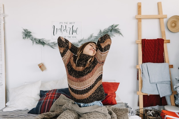 Photo happy young caucasian woman stretching in bed, waking up on christmas morning.