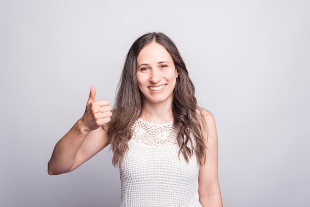 Happy young cheerful woman showing thumb up gesture and looking at the camera