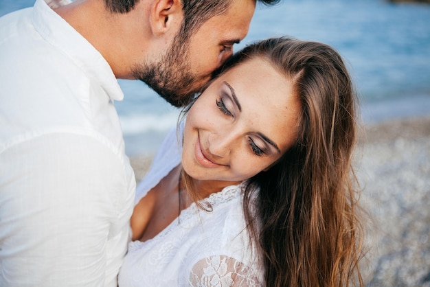 Happy young couple on the beach in love embracing and hugging smiling