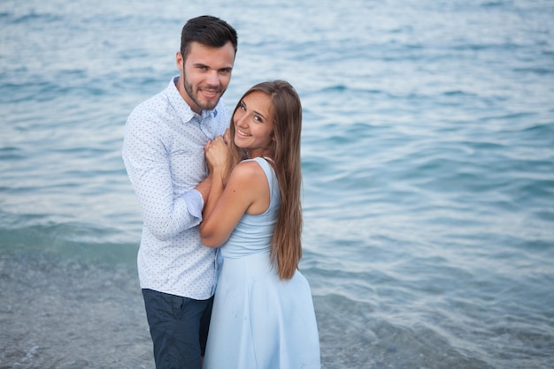 Happy young couple on the beach in love embracing and hugging smiling