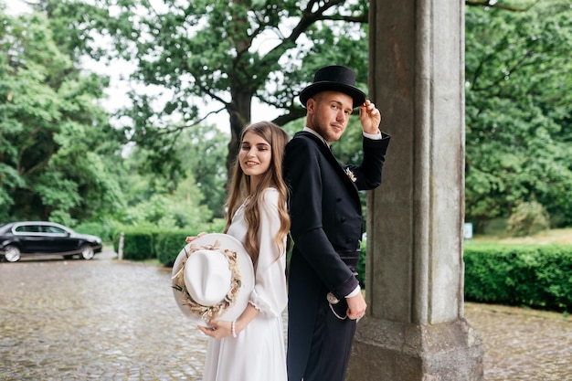 Happy young couple Brides in hats Young girl in a white wedding dress and hat with a bouquet of flowers Brides in the castle Bride and groom