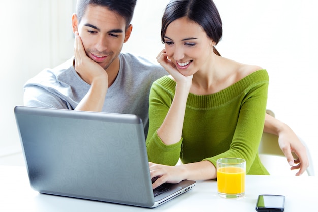 Happy young couple browsing internet at home