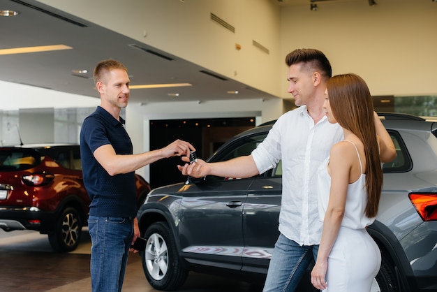 A happy young couple chooses a new car