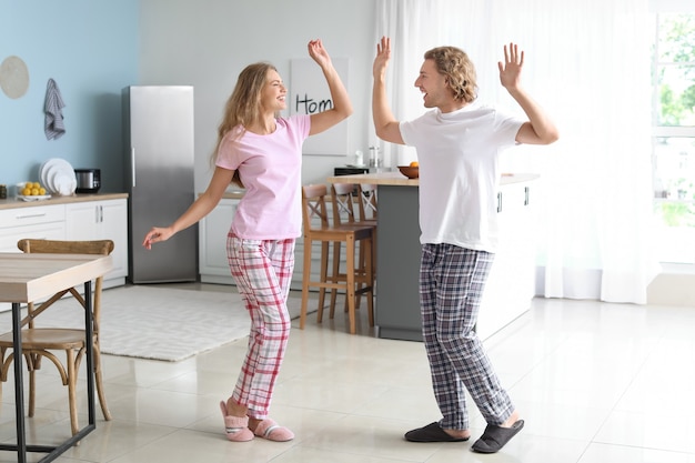 Photo happy young couple dancing in kitchen