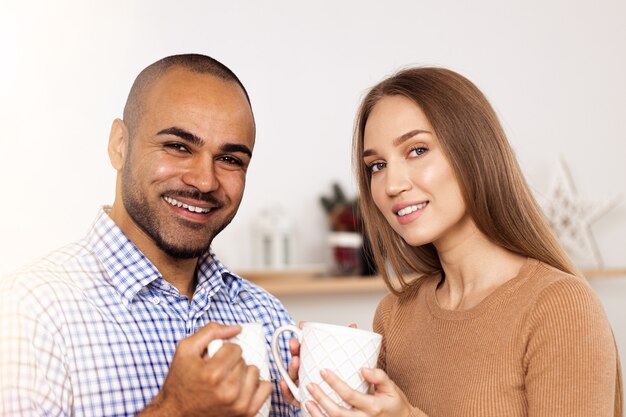 Happy young couple drinking hot beverage in kitchen