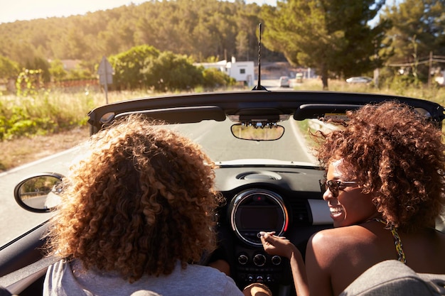 Happy young couple driving in an open top car Ibiza Spain