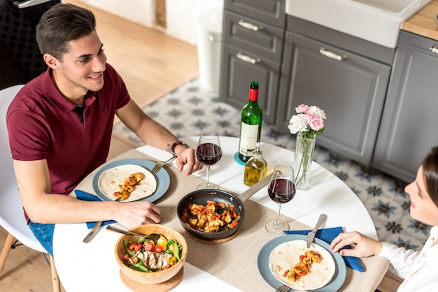 Happy young couple eating and drinking wine at home