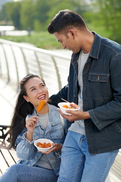 Happy young couple enjoying eating delicious street food outdoors