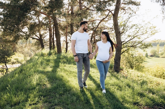 Happy young couple expecting baby in summer park