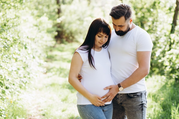 Happy young couple expecting baby in summer park