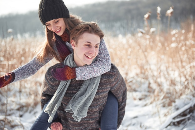 Happy young couple has fun on fresh snow at beautiful winter sunny day on vacation