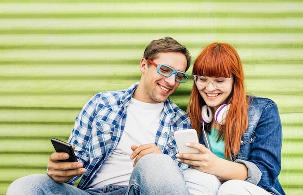 Happy young couple having fun with mobile smart phone at vintage grunge location